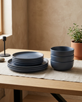 Stoneware plate and bowl set, empty and stacked on linen on a white oak table
