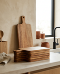 Set of acacia cutting boards, bare and stacked on a stone worktop