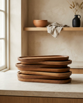 Oval acacia serving trays, bare and stacked on a stone worktop