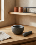 Granite grinding bowl and matching grinding stone, empty and clean, on a white oak worktop