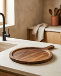 Solid wood round serving tray, bare and empty, on a stone worktop