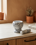 Dense stone grinding bowl and matching grinding stone, empty and clean, on a stone worktop