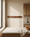 Slim walnut wall mounted magnetic storage strip, empty, on a plaster kitchen wall