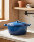 Enamel casserole pot with lid seated on top, clean and empty, on a stone worktop