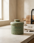 Porcelain butter crock, closed and empty, on a stone worktop